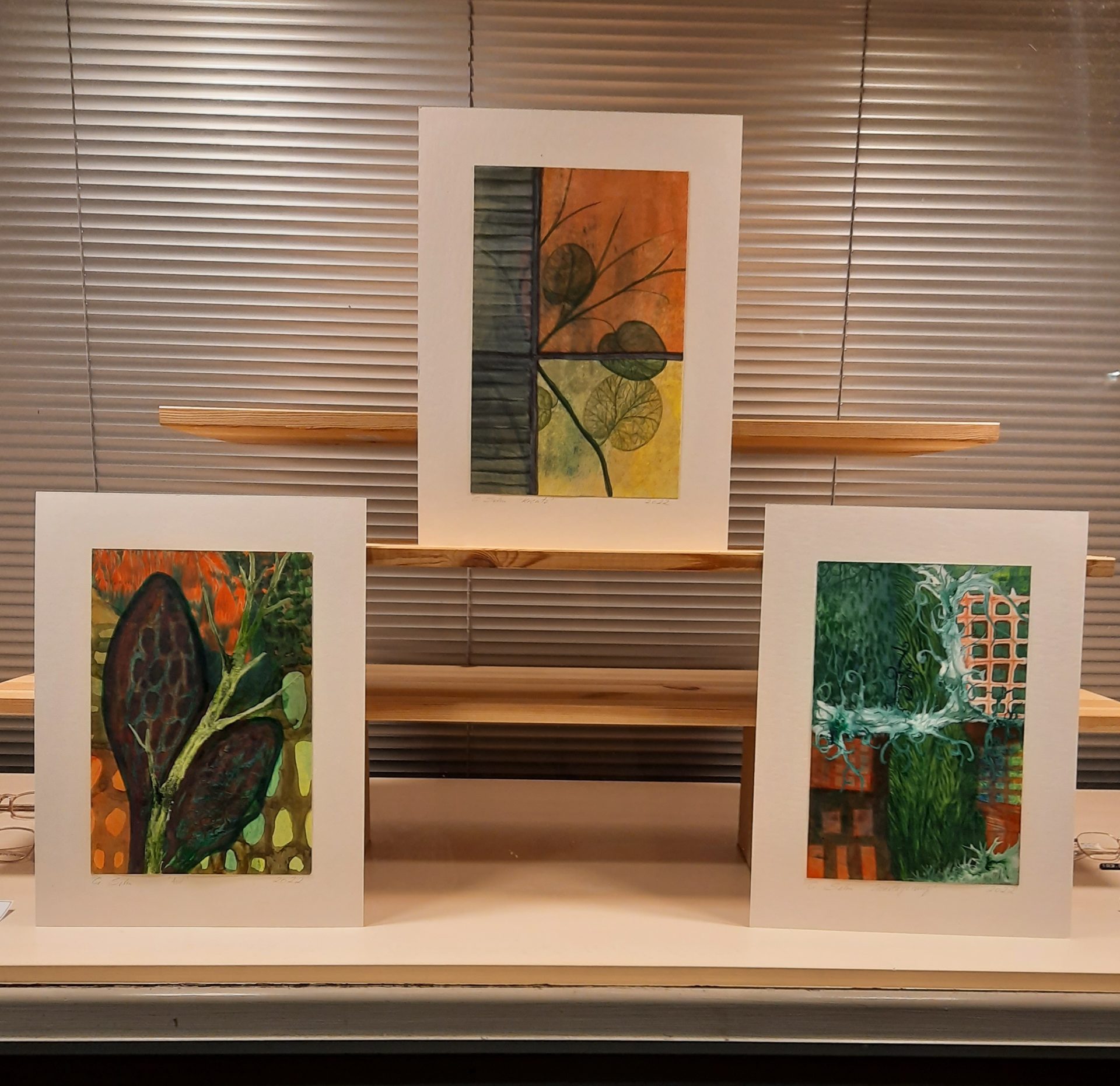 Drei abstrakte Gemälde auf Holzböden ausgestellt.