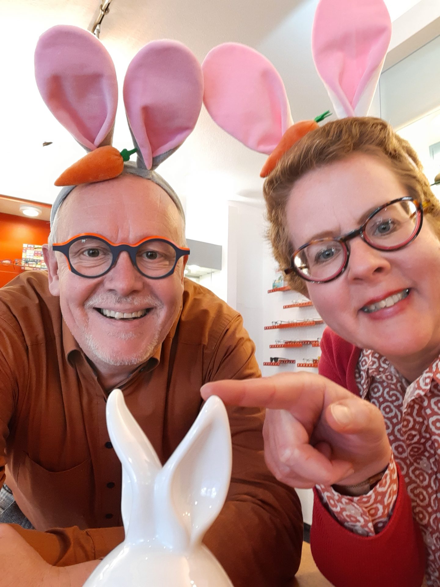 Menschen mit Hasenohren-Stirnbändern und Keramikhase, lächelnd.