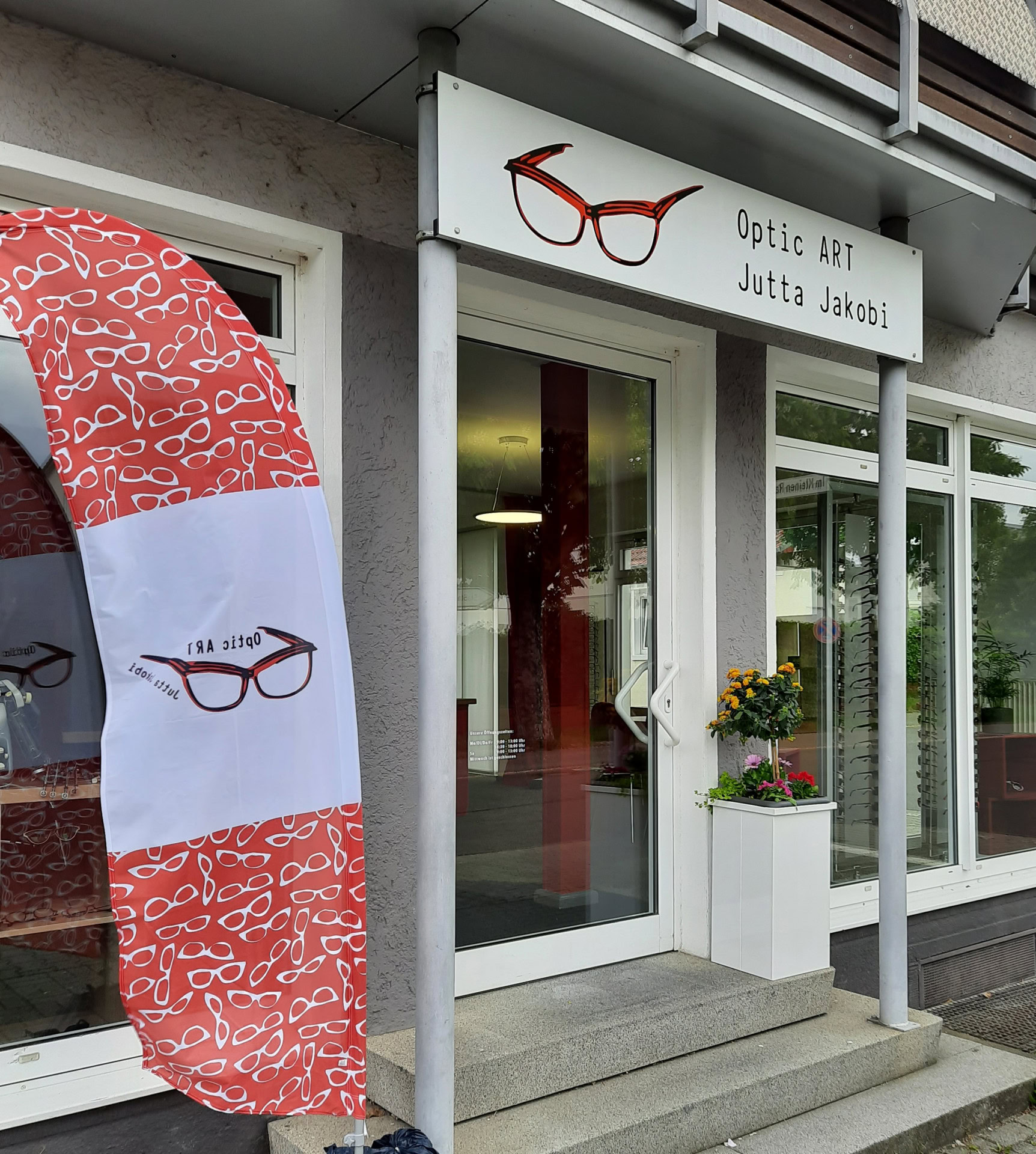 Optikerladen mit Brillenlogo und Werbefahne