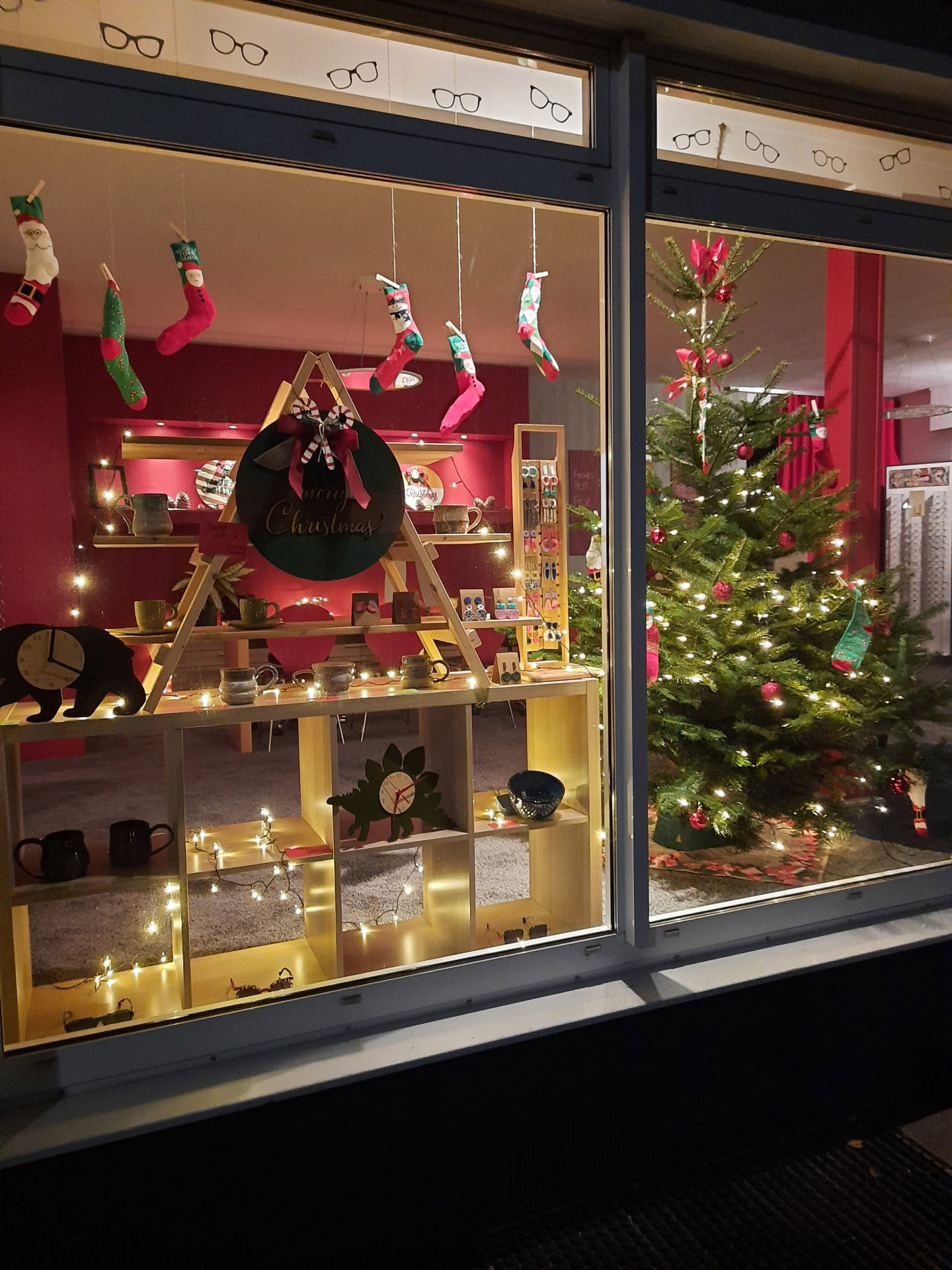 Dekoriertes Schaufenster mit Weihnachtsbaum und Lichtern.